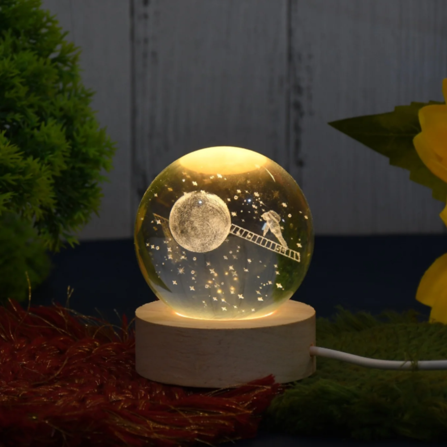 Decorative night light with moon and ladder design on a marble base, surrounded by plants.