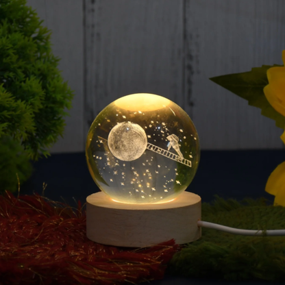 Decorative night light with moon and ladder design on a marble base, surrounded by plants.